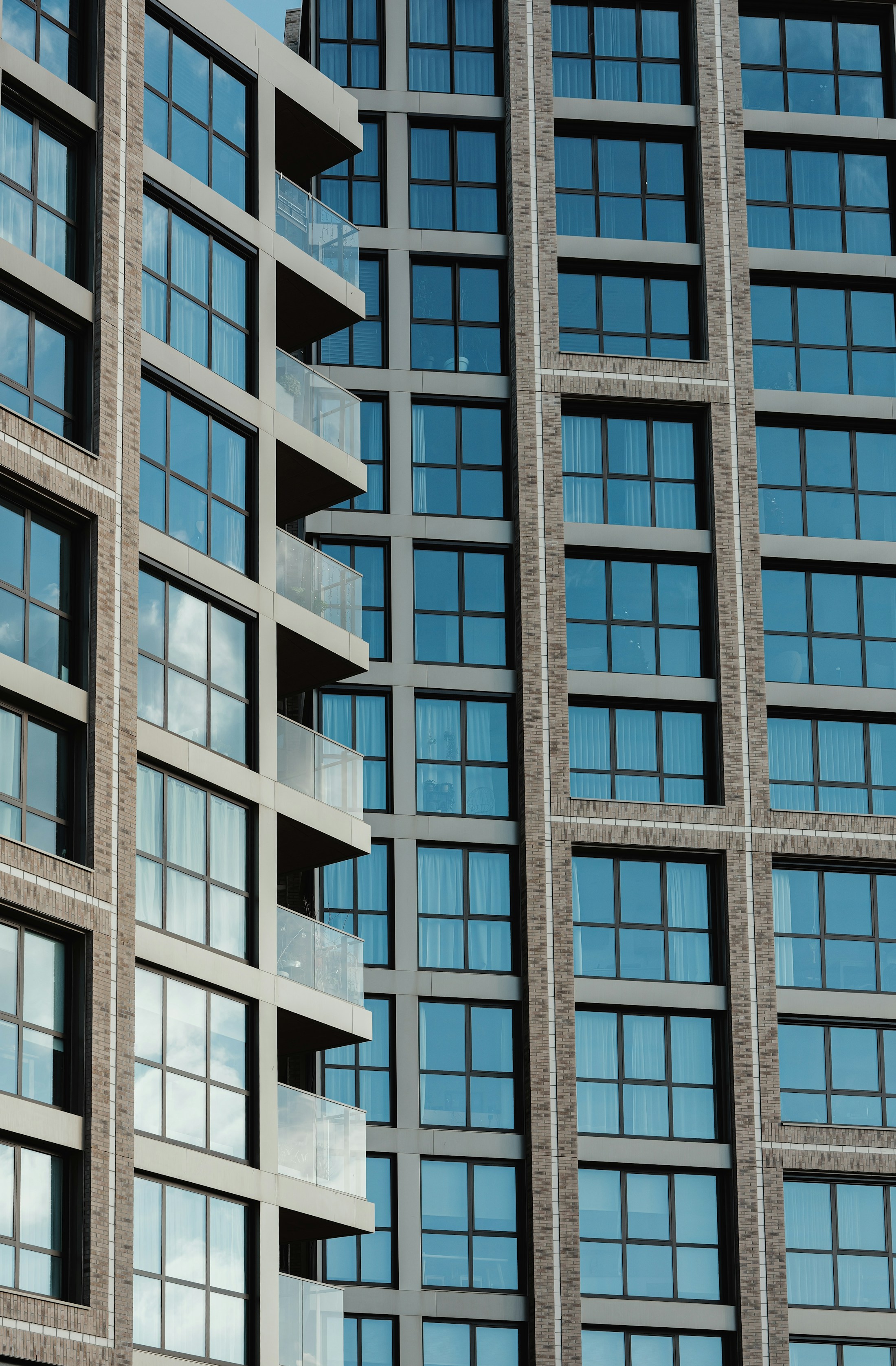 Real architectural photograph showing brickwork, windows and glass balconies on an apartment building